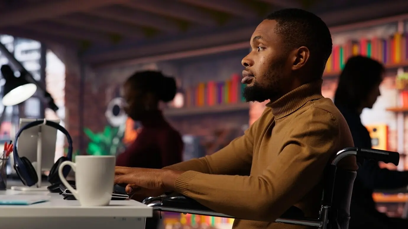 Hombre en silla de ruedas trabajando en una agencia de tecnología de IA inclusiva